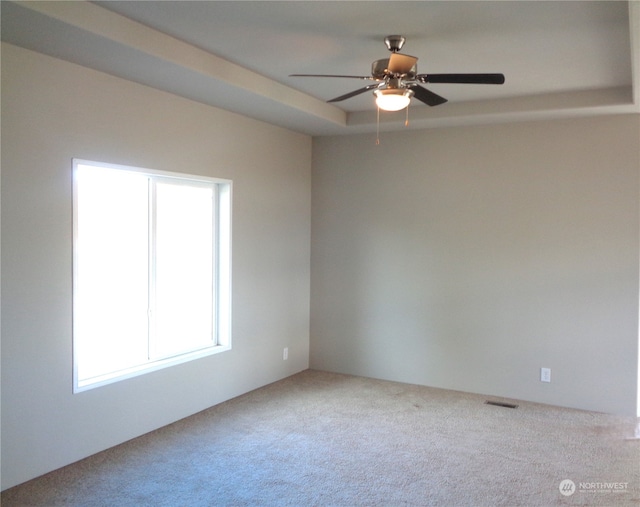 carpeted empty room with a tray ceiling and ceiling fan