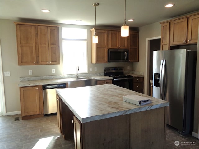 kitchen with pendant lighting, sink, a kitchen island, hardwood / wood-style flooring, and appliances with stainless steel finishes