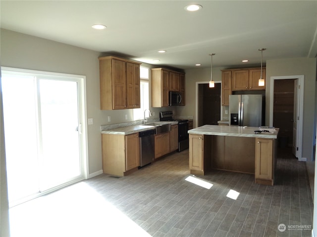 kitchen with pendant lighting, a kitchen island, plenty of natural light, and black appliances