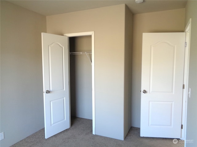 unfurnished bedroom with light carpet and a closet