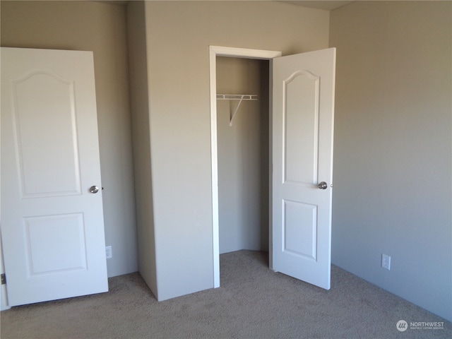 unfurnished bedroom with light colored carpet and a closet