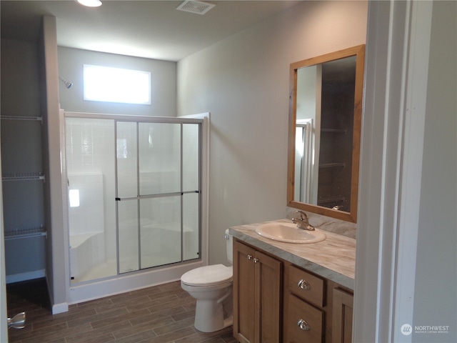 bathroom with hardwood / wood-style floors, vanity, a shower with shower door, and toilet