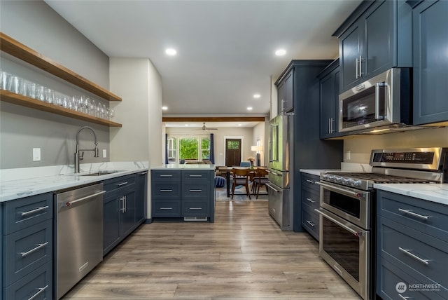 kitchen featuring light wood-type flooring, light stone counters, sink, kitchen peninsula, and stainless steel appliances