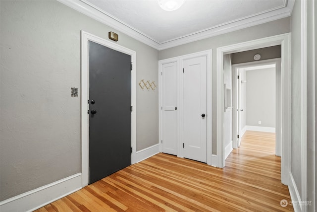 foyer with baseboards, light wood-type flooring, and ornamental molding
