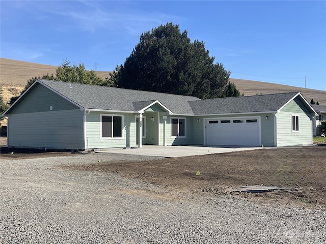 ranch-style home with an attached garage, a shingled roof, and concrete driveway