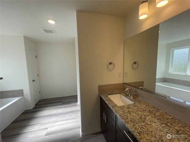 bathroom featuring vanity, a washtub, and hardwood / wood-style flooring