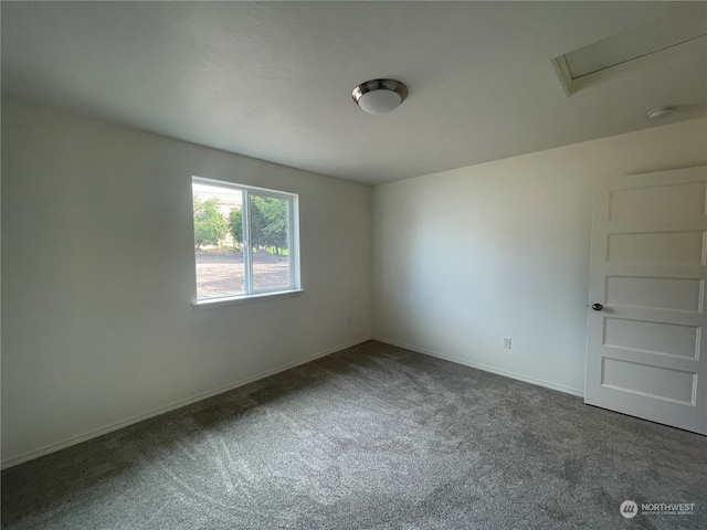 empty room with carpet flooring, attic access, and baseboards