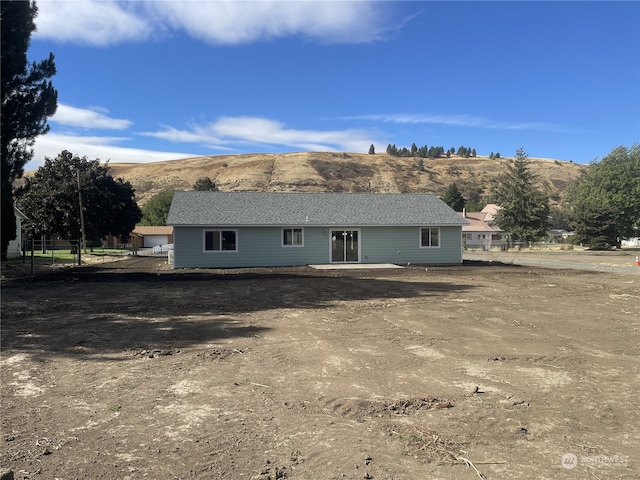 back of property featuring a mountain view and fence