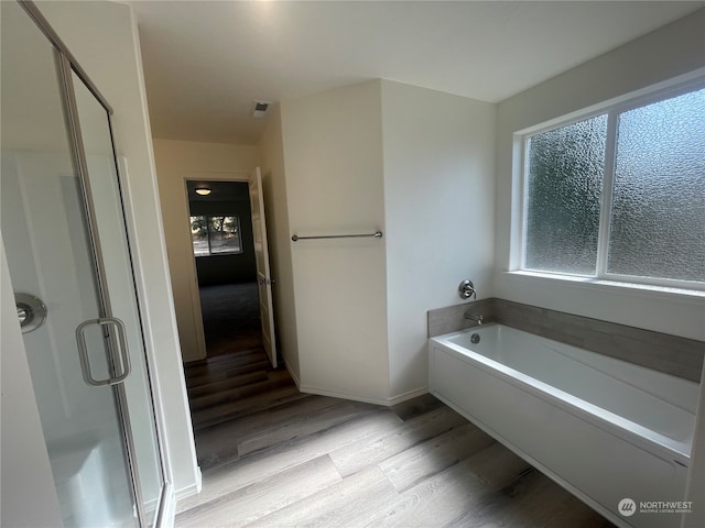 bathroom featuring a healthy amount of sunlight, shower with separate bathtub, and hardwood / wood-style floors