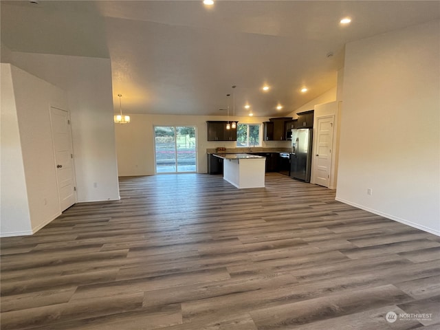 kitchen featuring dark wood-style floors, recessed lighting, open floor plan, a kitchen island, and stainless steel fridge