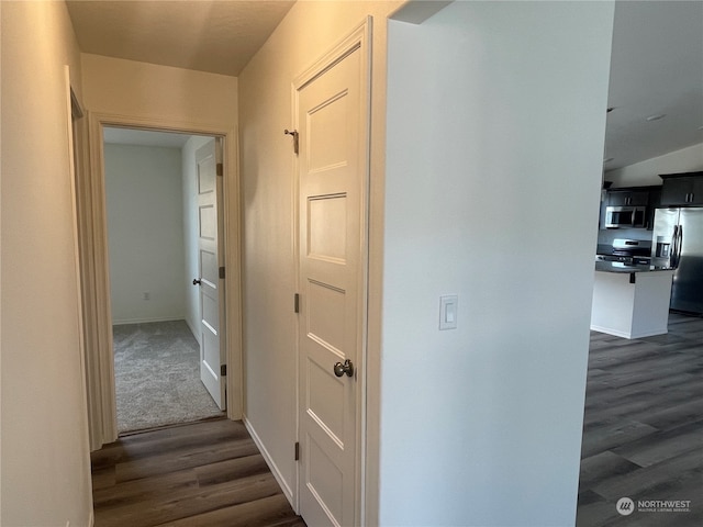 hallway featuring dark wood-type flooring and baseboards