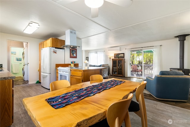 dining space featuring ceiling fan, dark hardwood / wood-style floors, a wood stove, and a wall unit AC