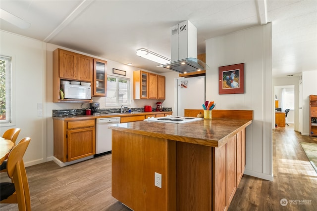 kitchen featuring a healthy amount of sunlight, white appliances, light hardwood / wood-style flooring, and island range hood