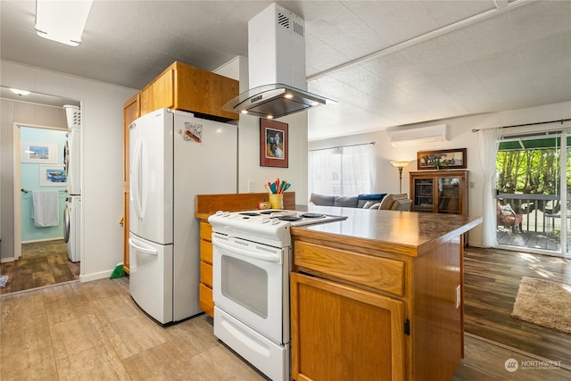 kitchen featuring light hardwood / wood-style floors, white appliances, island exhaust hood, washer / dryer, and a wall mounted AC