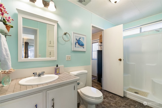 bathroom featuring walk in shower, plenty of natural light, vanity, and toilet