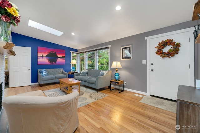 living room with vaulted ceiling with skylight and light hardwood / wood-style floors