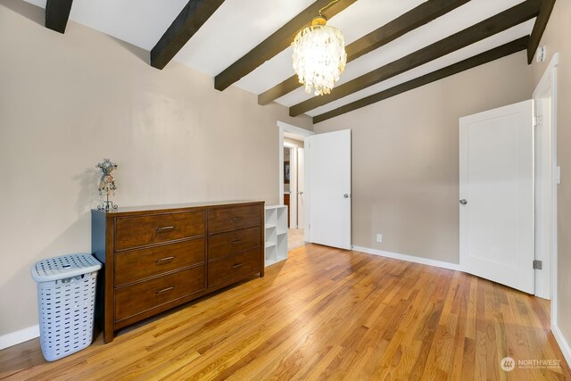 bedroom with an inviting chandelier, light wood-type flooring, and vaulted ceiling with beams