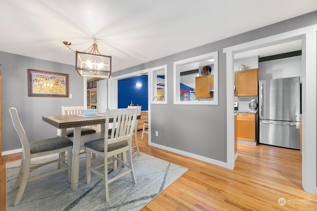 dining space featuring light hardwood / wood-style flooring and a notable chandelier