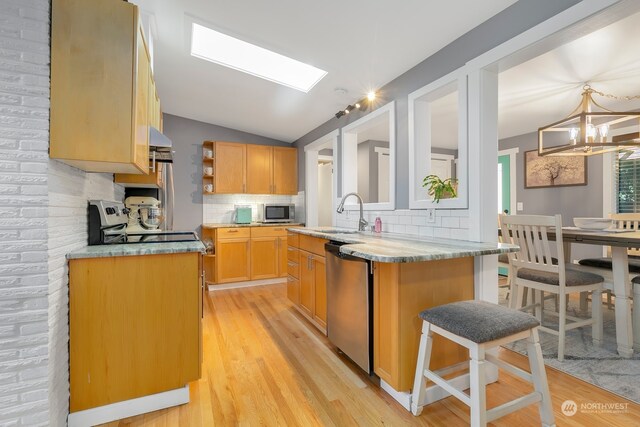 kitchen featuring appliances with stainless steel finishes, tasteful backsplash, light wood-type flooring, a center island, and sink