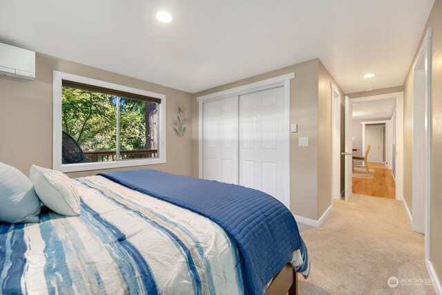 bedroom with light colored carpet, a closet, and a wall mounted air conditioner