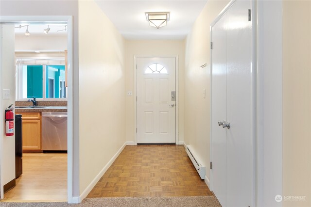 doorway with a baseboard radiator, sink, and light parquet floors