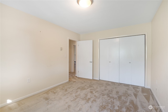 unfurnished bedroom featuring light carpet and a closet