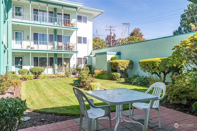 exterior space with a balcony, a lawn, and a patio