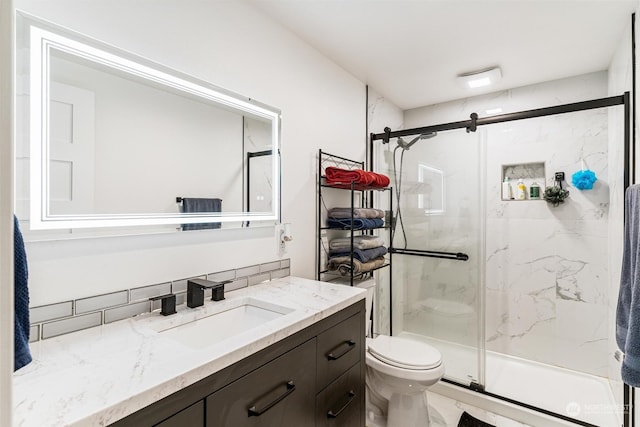 bathroom featuring vanity, toilet, an enclosed shower, and tasteful backsplash