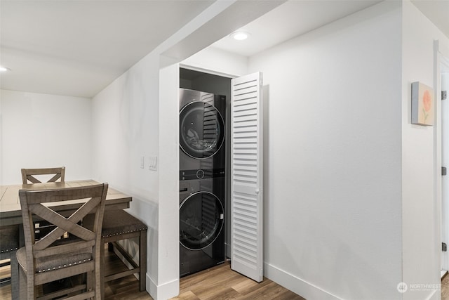 laundry room featuring stacked washer / drying machine and light hardwood / wood-style floors