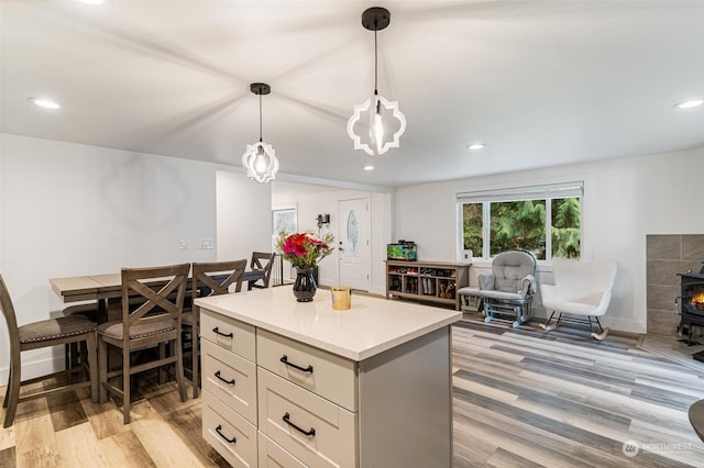 kitchen with pendant lighting, light wood-type flooring, a wood stove, and a center island