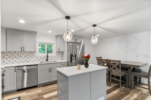 kitchen featuring light hardwood / wood-style floors, sink, hanging light fixtures, gray cabinetry, and stainless steel appliances