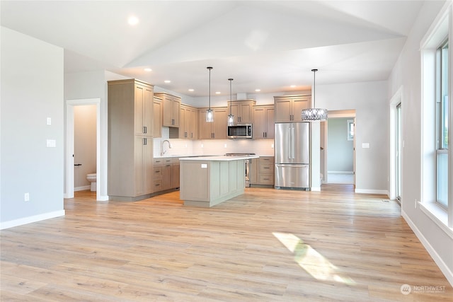 kitchen with a kitchen island, light hardwood / wood-style floors, appliances with stainless steel finishes, and decorative light fixtures