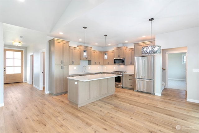 kitchen featuring pendant lighting, sink, appliances with stainless steel finishes, a center island, and light wood-type flooring