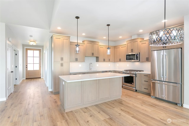 kitchen featuring pendant lighting, sink, a kitchen island, premium appliances, and light wood-type flooring