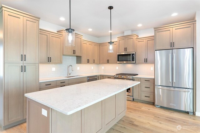 kitchen with light wood-type flooring, sink, stainless steel appliances, and decorative light fixtures