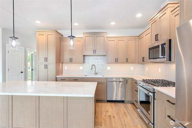 kitchen with pendant lighting, sink, stainless steel appliances, light brown cabinetry, and light wood-type flooring