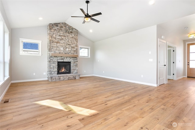 unfurnished living room with ceiling fan, a stone fireplace, plenty of natural light, and light hardwood / wood-style floors