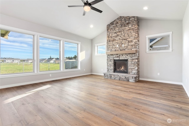 unfurnished living room with light hardwood / wood-style floors, ceiling fan, vaulted ceiling, and a fireplace