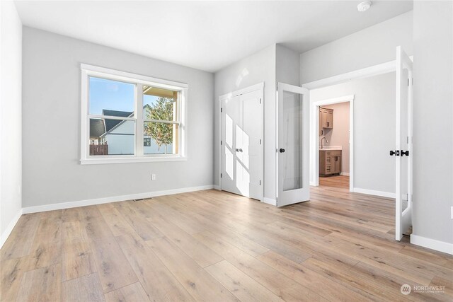 unfurnished bedroom with light hardwood / wood-style floors and sink