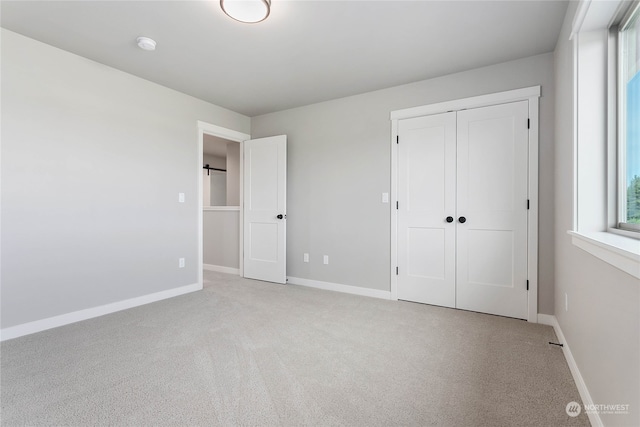 unfurnished bedroom with light carpet and a closet