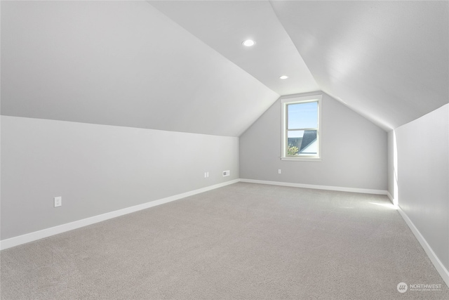 bonus room with light carpet and vaulted ceiling