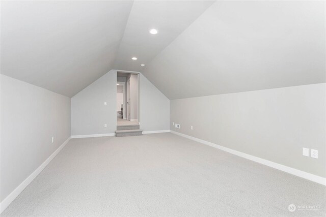 bonus room with vaulted ceiling and carpet flooring