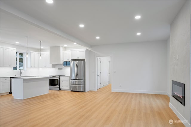 kitchen featuring white cabinetry, a center island, hanging light fixtures, stainless steel appliances, and light hardwood / wood-style floors