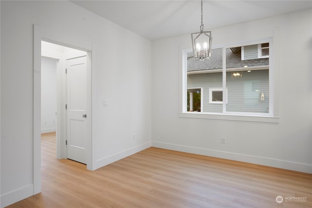 spare room featuring light hardwood / wood-style flooring and a notable chandelier