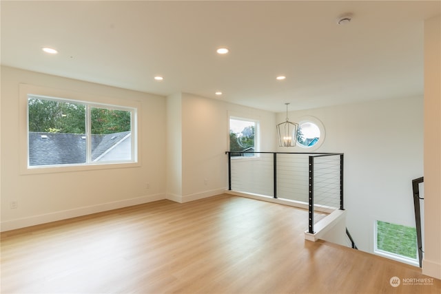 unfurnished room with a notable chandelier and light wood-type flooring