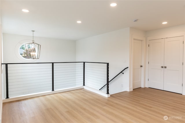 spare room with light wood-type flooring and an inviting chandelier