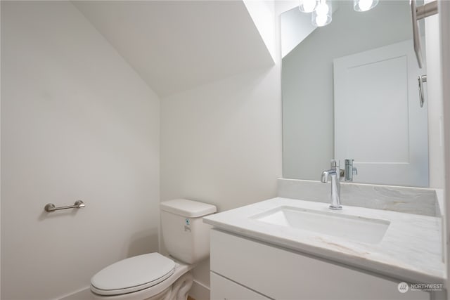 bathroom with vanity, toilet, and lofted ceiling