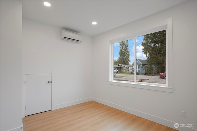 unfurnished room featuring light hardwood / wood-style floors and an AC wall unit