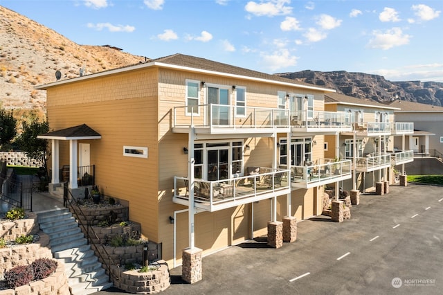 back of property with a garage, a balcony, and a mountain view