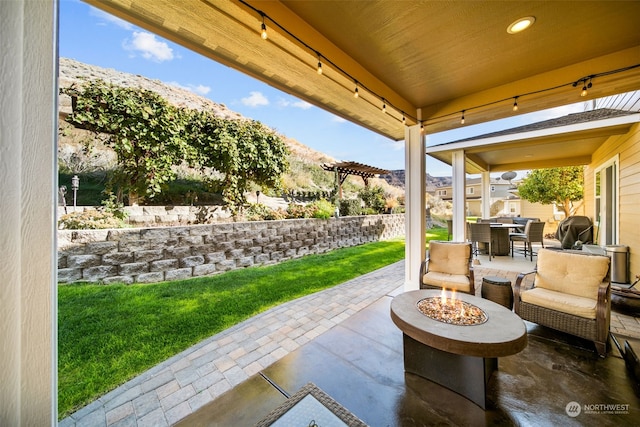 view of patio featuring an outdoor fire pit and a mountain view